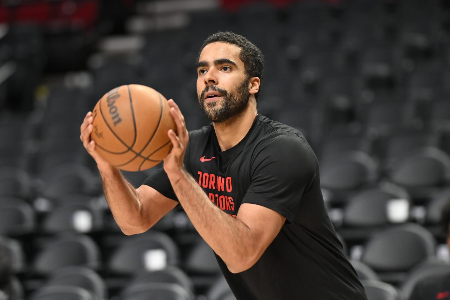 Jontay Porter is wearing a black t-shirt and is crouched with a basketball in his hands, poised to shoot the ball.