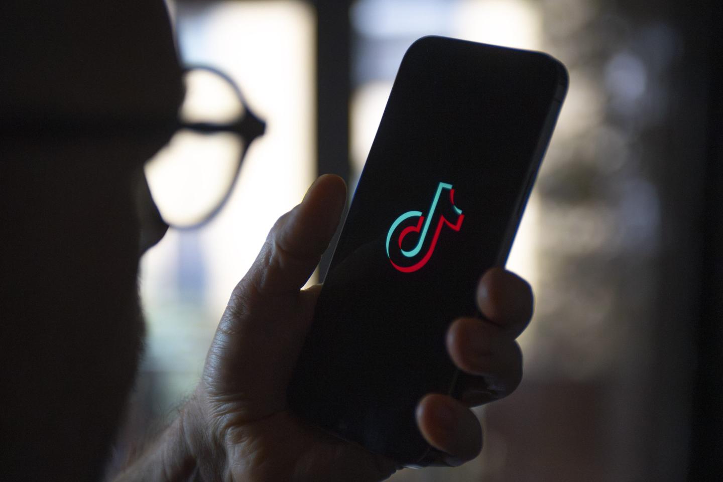 Person holding a phone with TikTok's logo on the screen