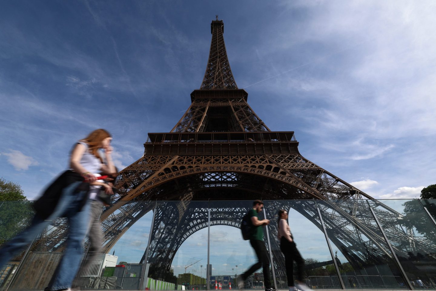 Pedestrians walk past the Eiffel Tower in Paris on April 12, 2024.