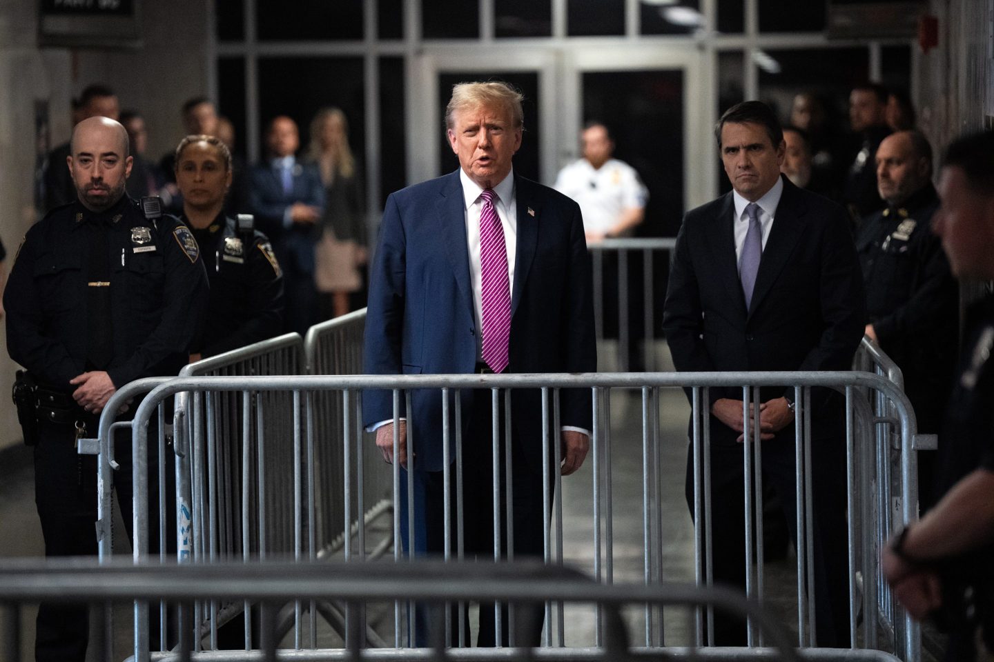 Donald Trump stands behind metal fence