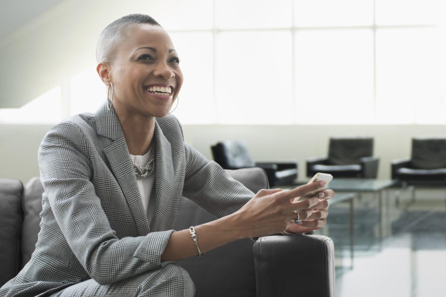 Smiling executive sitting on a couch holding a cellphone
