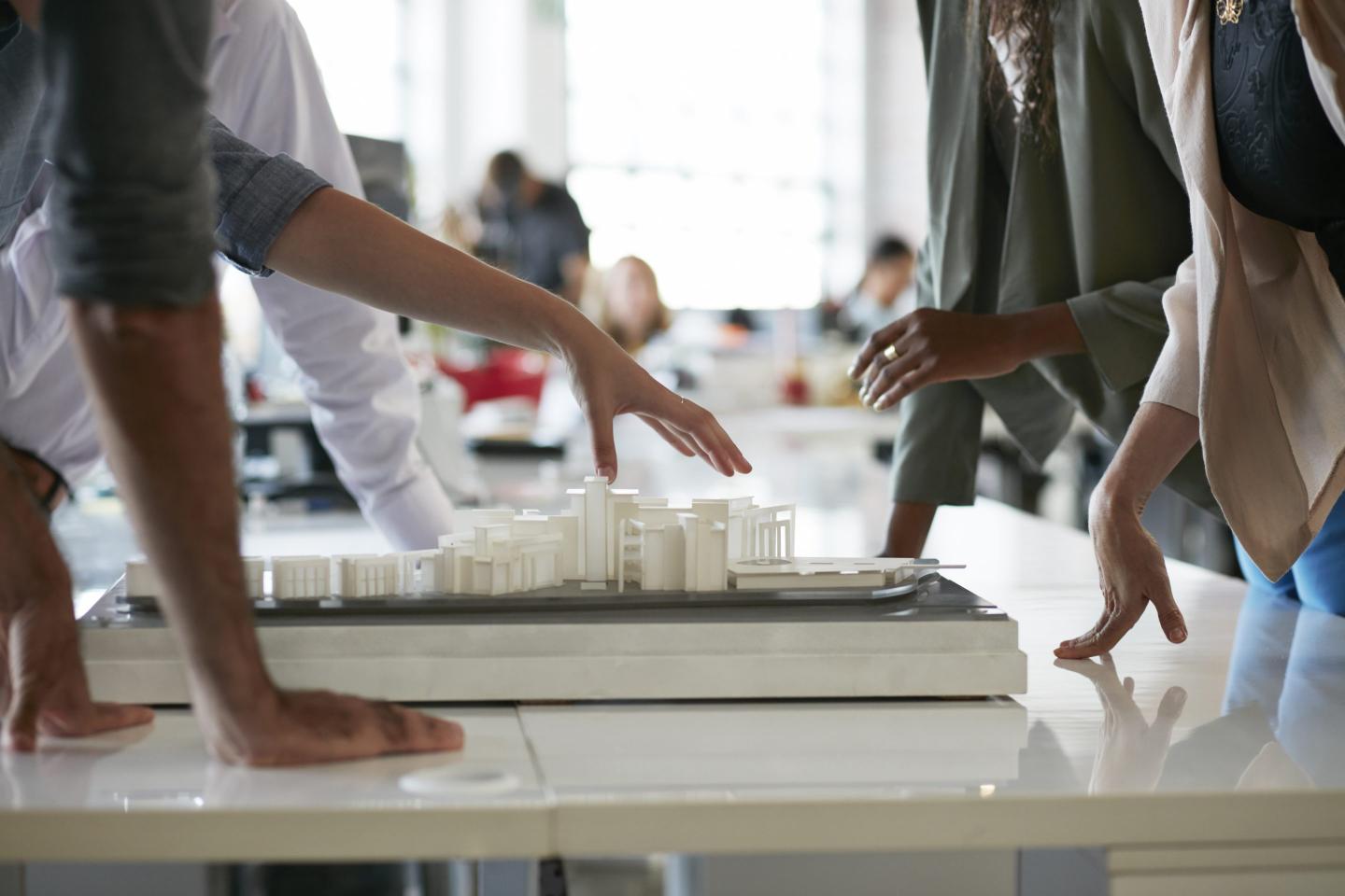 Close-up of co-workers gathered around architectural model