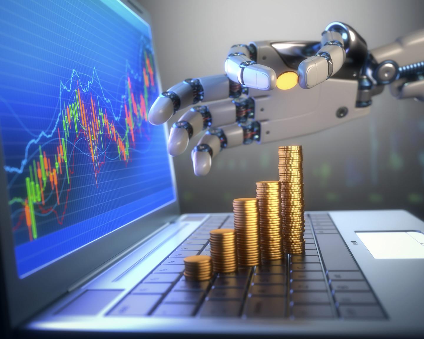 Coins on a laptop computer with a robotic hand.
