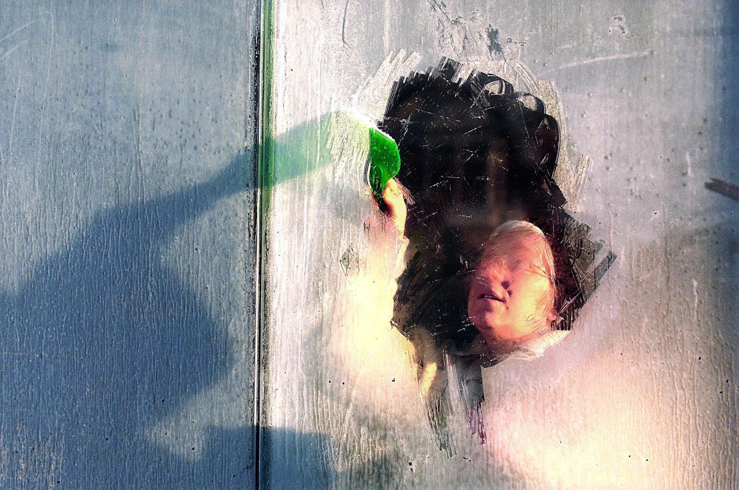 A person scraping ice from a foggy window.