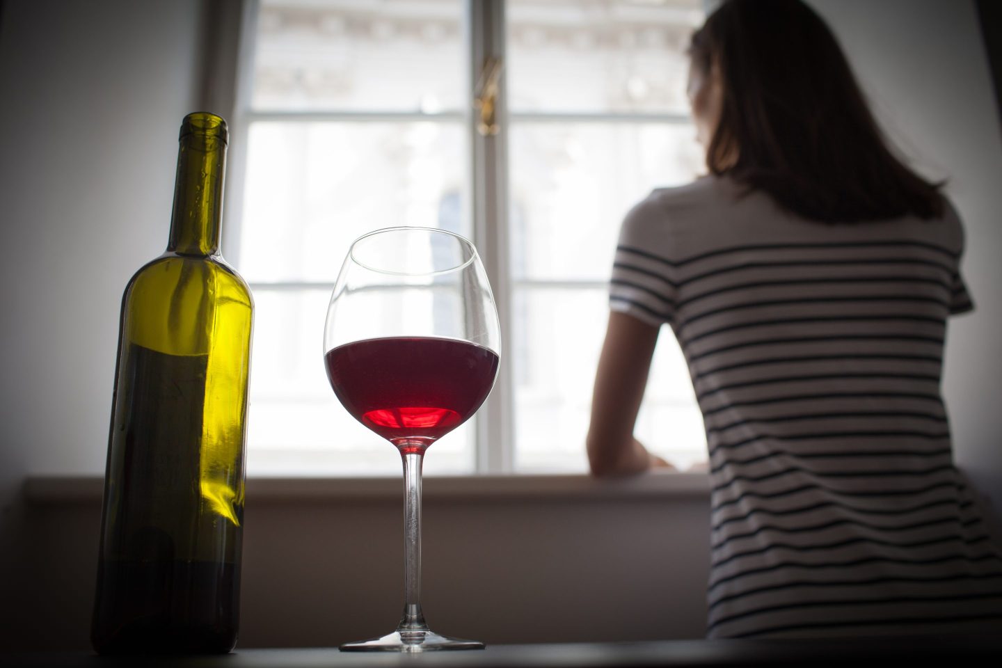 Woman drinking wine alone in a dark room