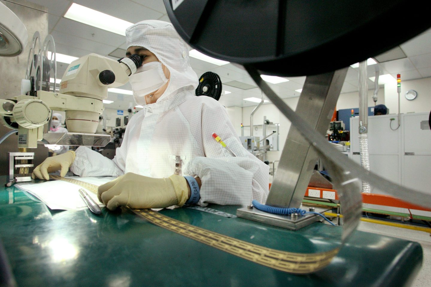 A worker monitors computerized machinery used to produce electronic smart cards at an AIC Semiconductor factory in Kulim, Malaysia.