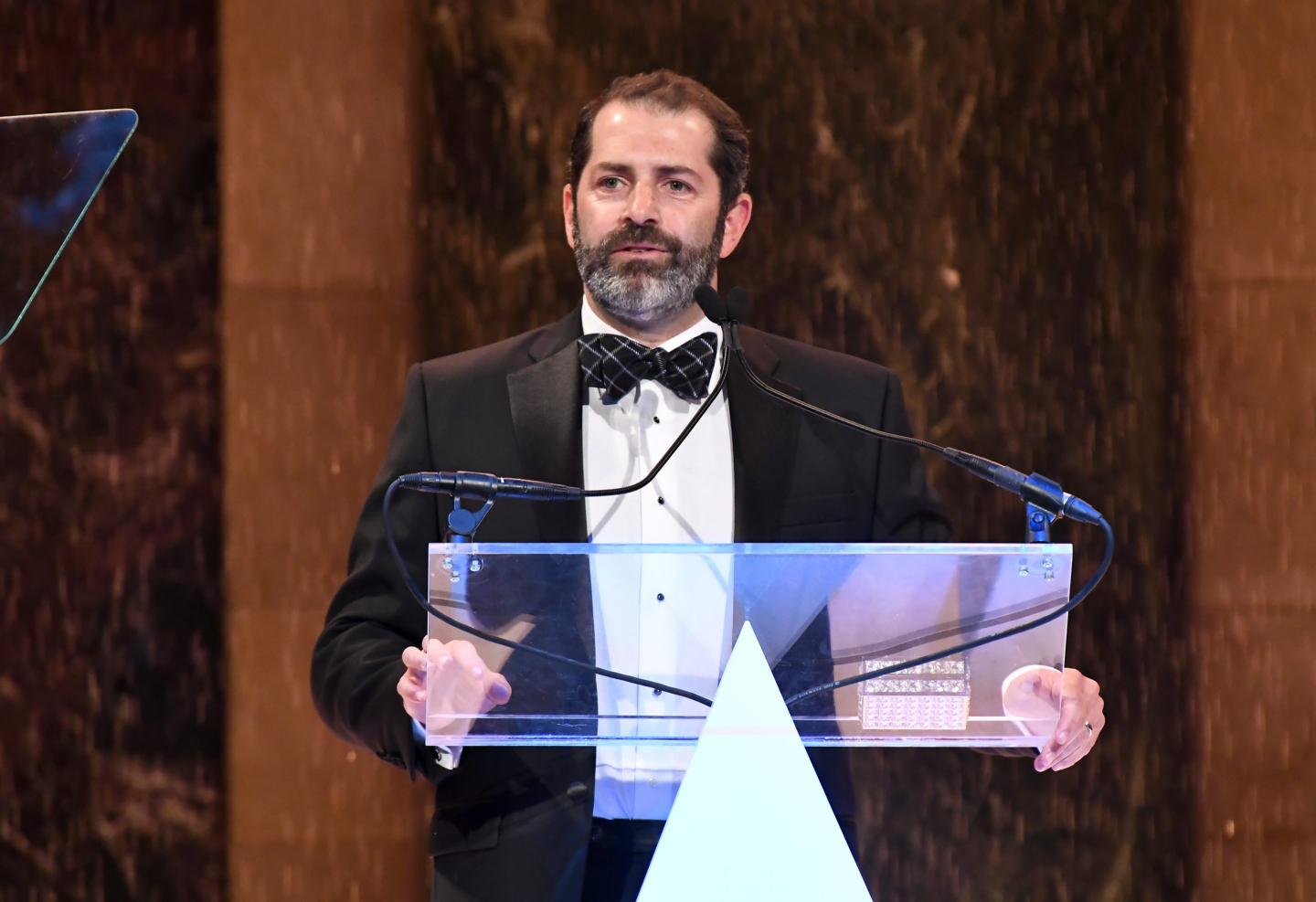 Former Allbirds CEO Joey Zwillinger is wearing a tuxedo and standing at a glass podium.