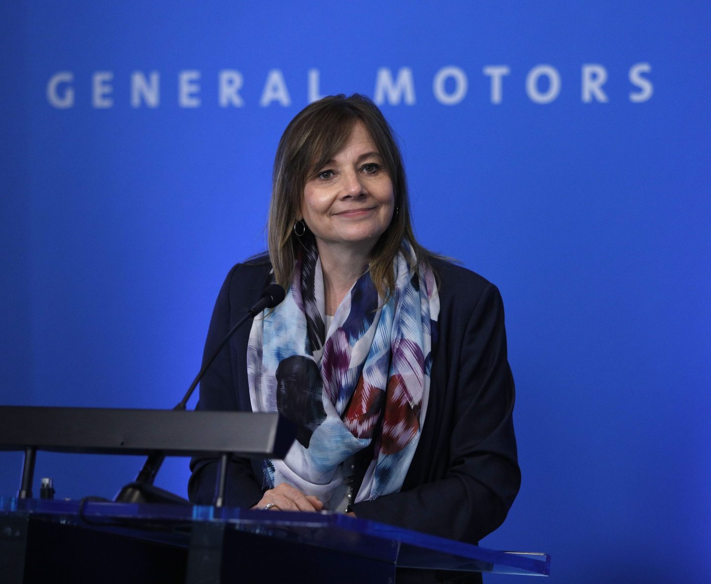 General Motors CEO Mary Barra speaking at a podium.