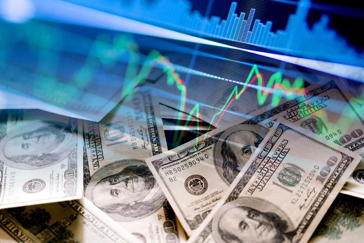 Illustration showing a pile of $100 bills against a background of a stock market chart