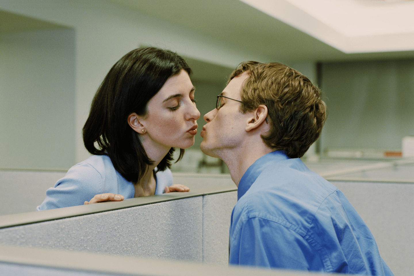 Man and woman in seperate cubicles, kissing - stock photo