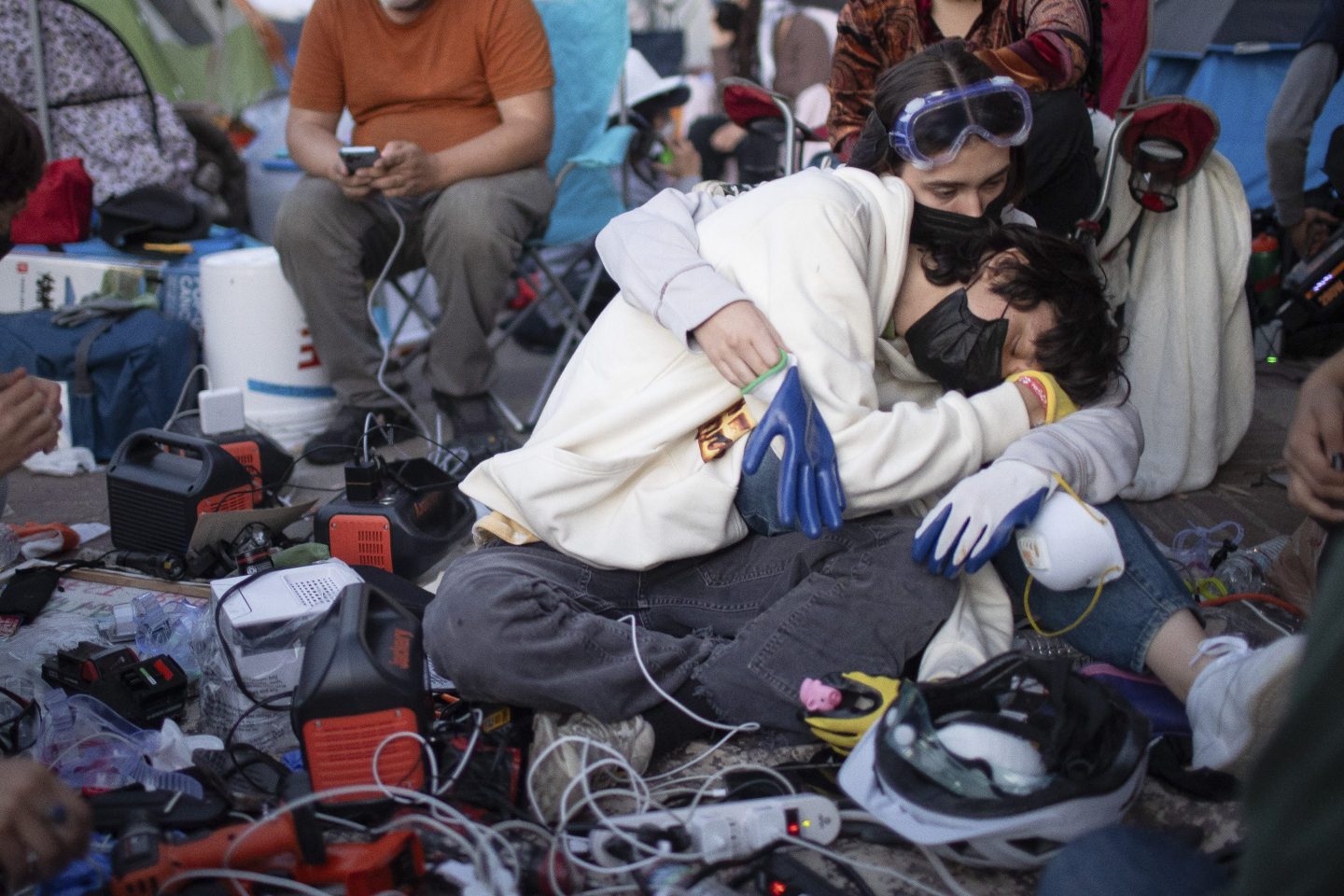 Pro-Palestinian demonstrators embrace while charging devices at an encampment on the UCLA campus on May 1, 2024, in Los Angeles.