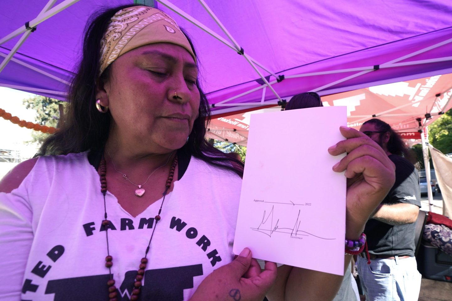 Farmworker Xochilt Nunez holds a copy of the bill signed by Gov. Gavin Newsom aimed at making it easier for farmworkers to unionize, in Sacramento, on Sept. 28, 2022.