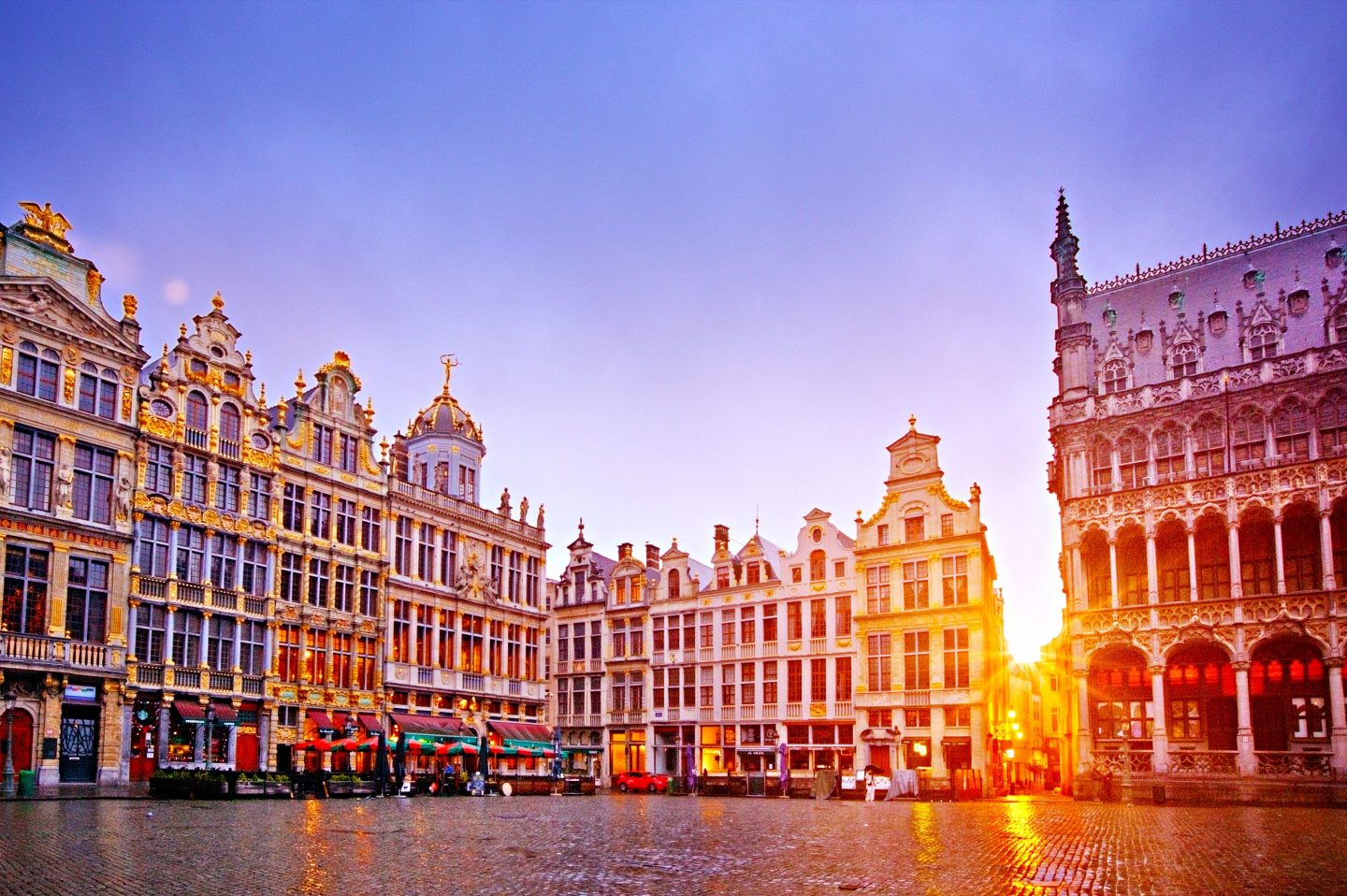 The rising sun shines through a gap in the old buildings in the central square in Brussels
