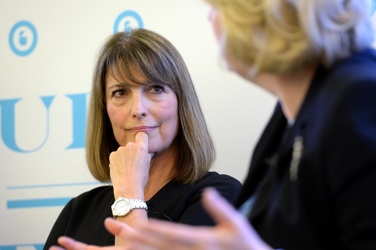 Carolyn McCall listens intently to a fellow panelist at an event, with her hand on her chin.