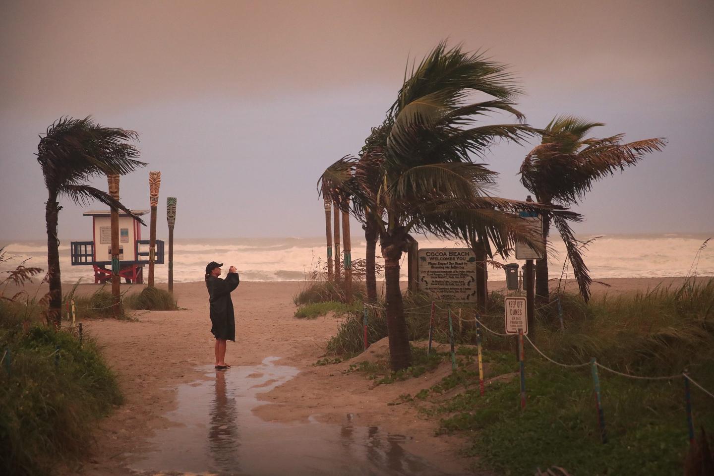 A woman standing on a beach during a hurricane.