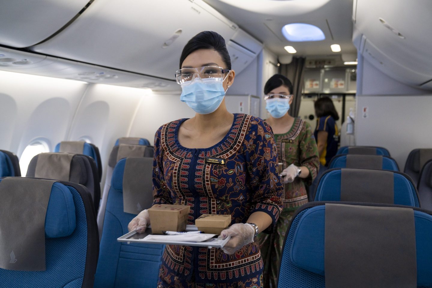 A flight attendant on a Singapore Airlines plane carries a tray of food down the aisle.