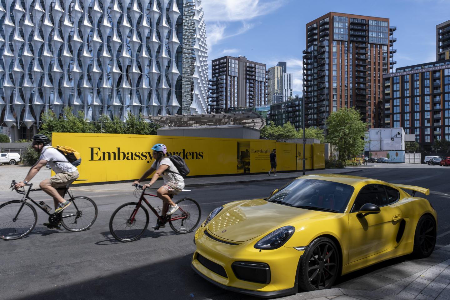 Yellow Porsche supercar parked beside a yellow hoarding for the Embassy Gardens residential development beside the US Embassy