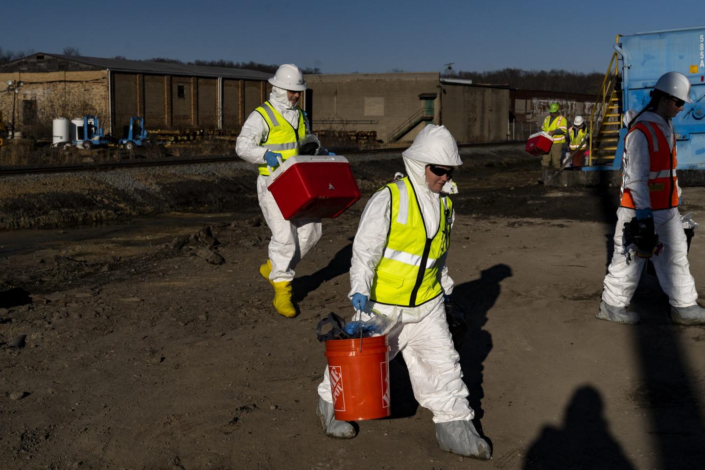 EPA contractors walk back to their cars with collected soil samples from the derailment site