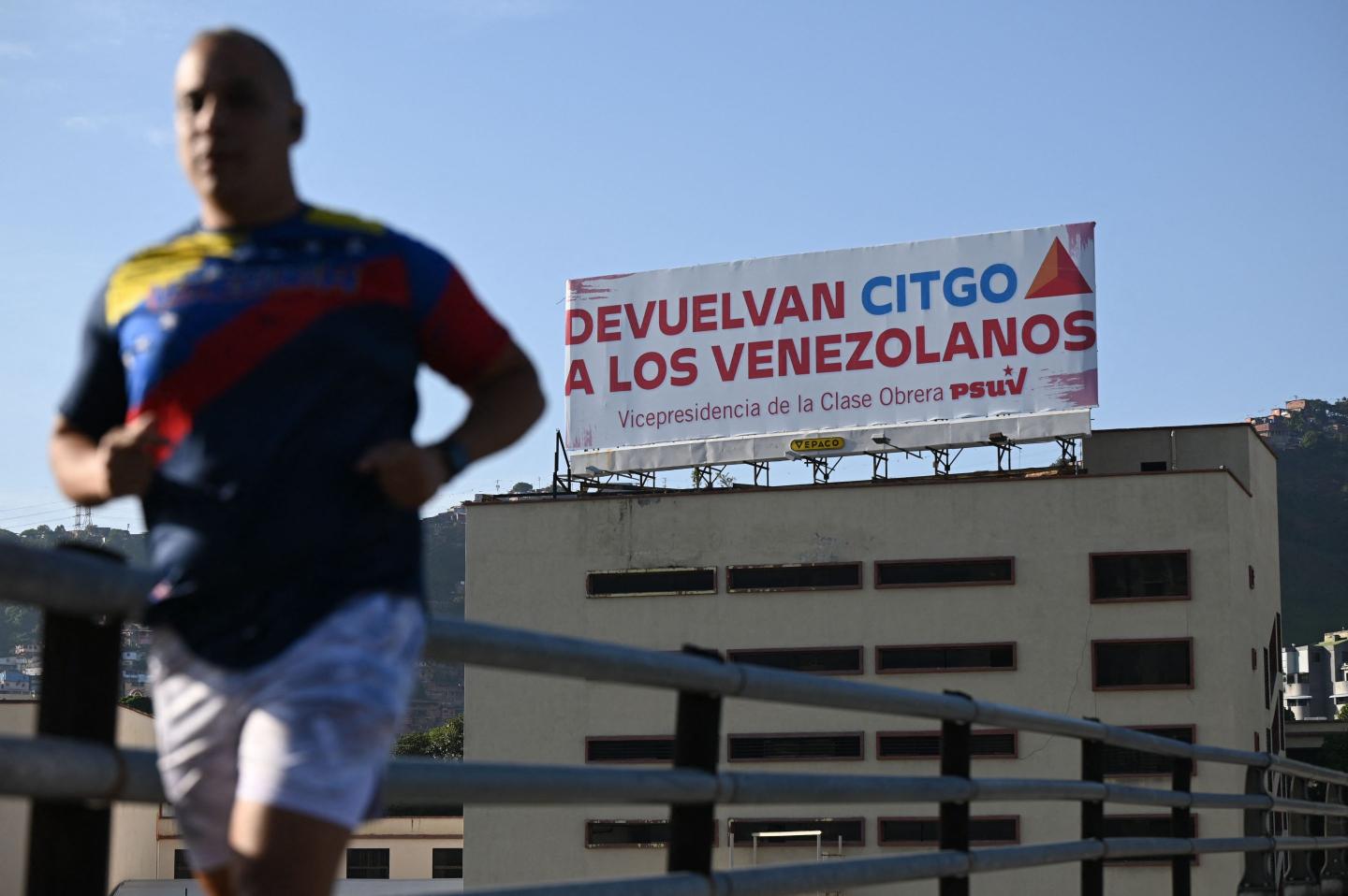 A man jogs past a billboard of the United Socialist Party of Venezuela (PSUV), reading "Return CITGO to the Venezuelans," in Caracas on June 27, 2023. 
