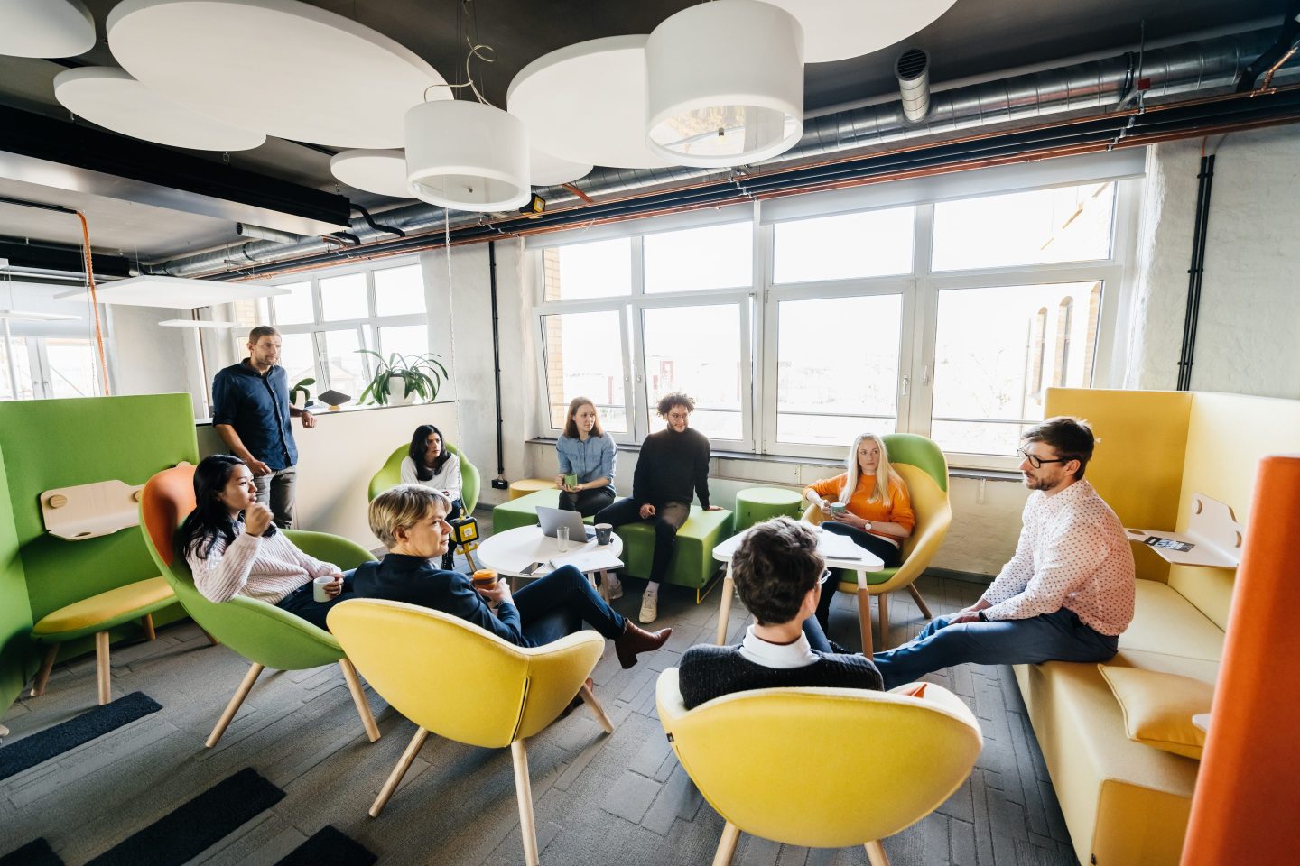 A seminar between a team sitting together on colorful chairs in a modern office space.