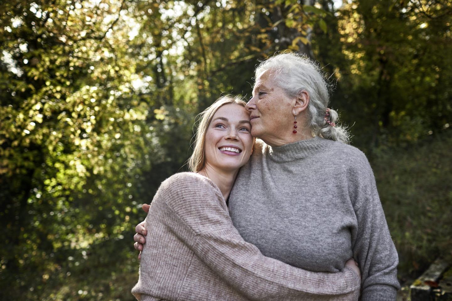 Grandmother and adult granddaughter embracing in garden