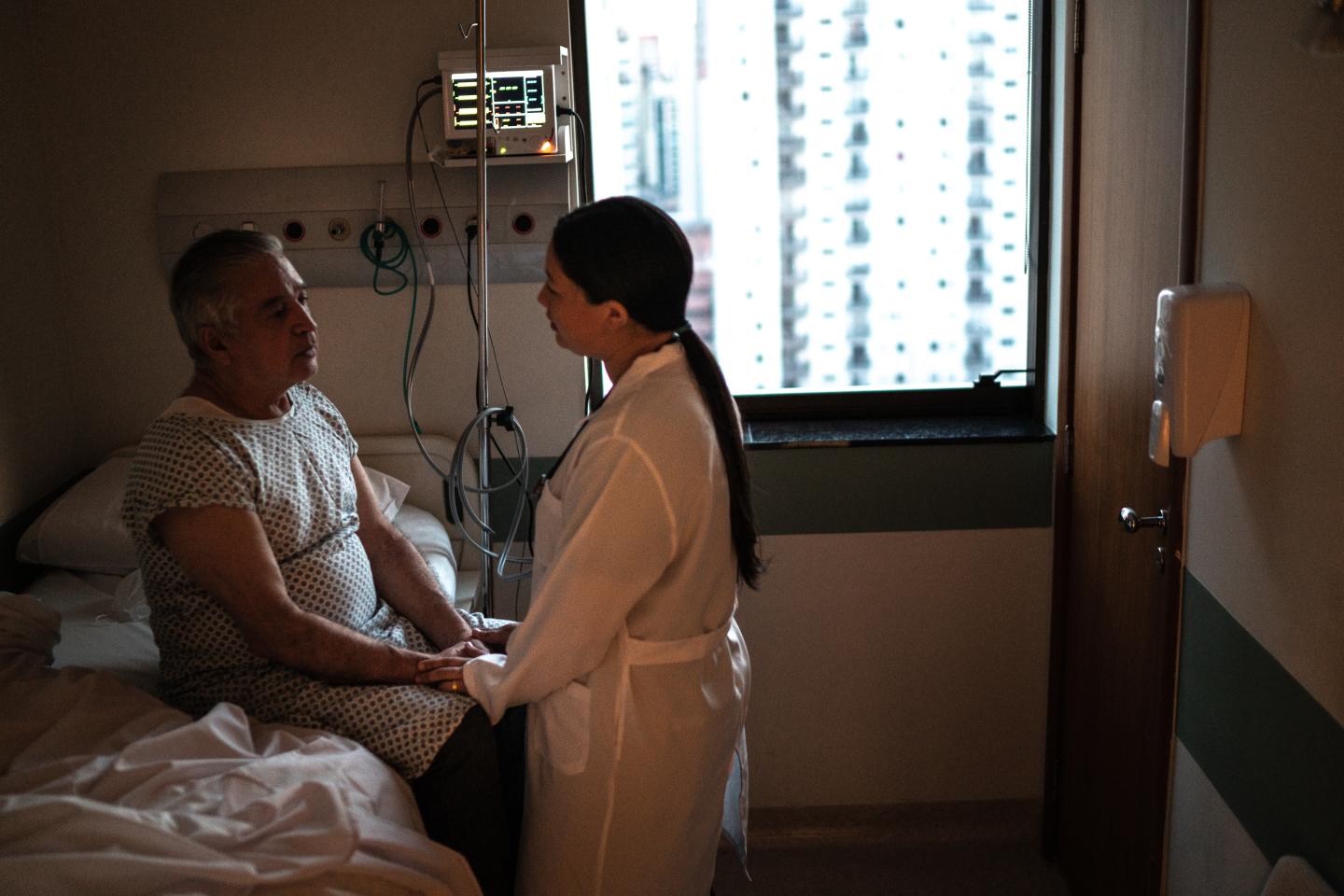 Doctor with patient at hospital bedside