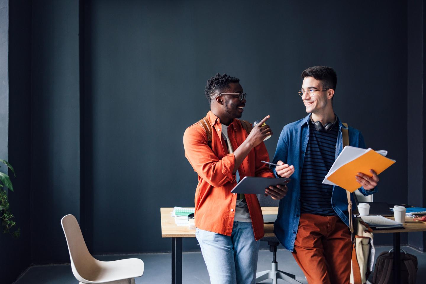 Two coworkers chat at an office.