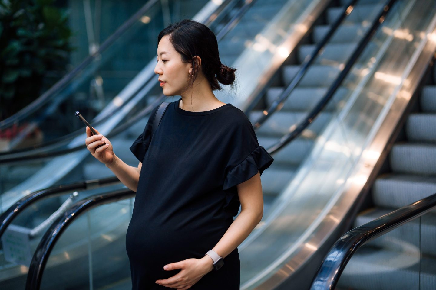 Pregnant woman walking with phone in hand