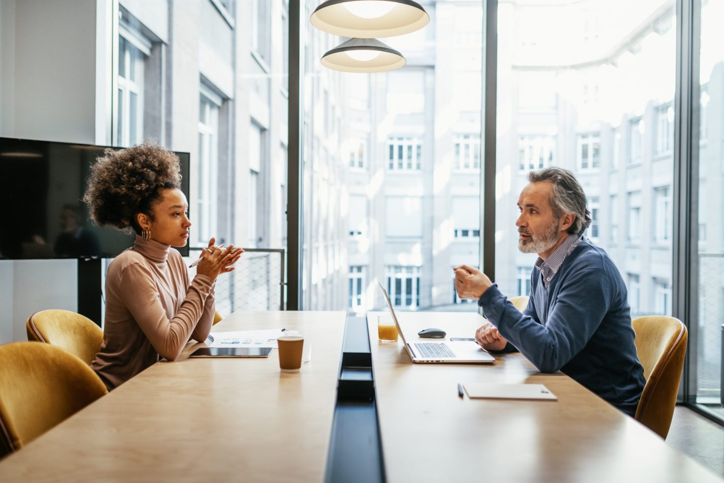 Gen Z worker at a table opposite an older worker