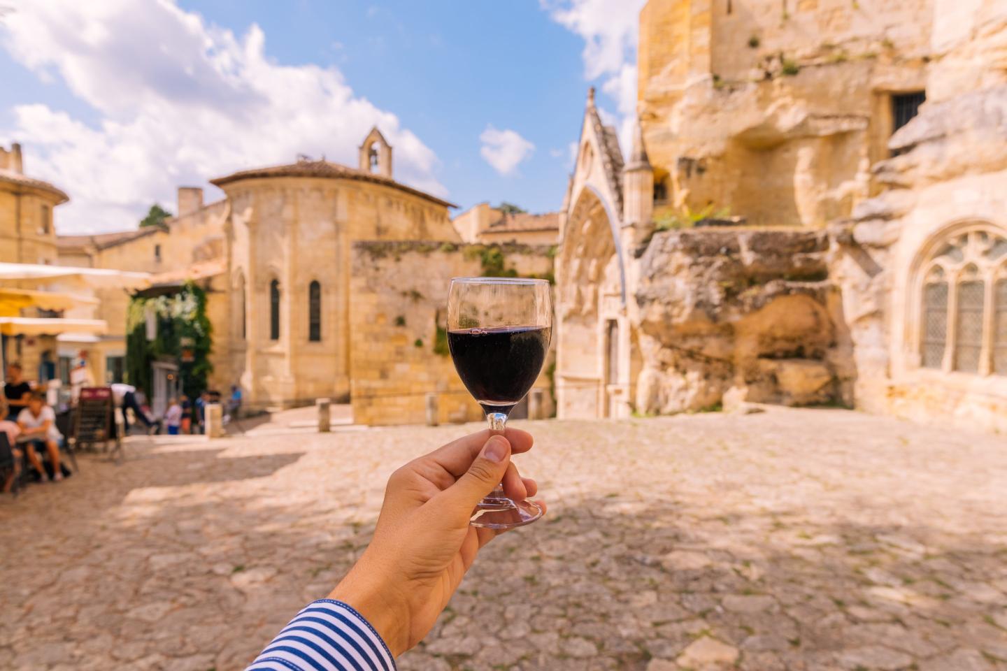Man drinking red wine in Saint-Emilion village, personal perspective view, Bordeaux, France