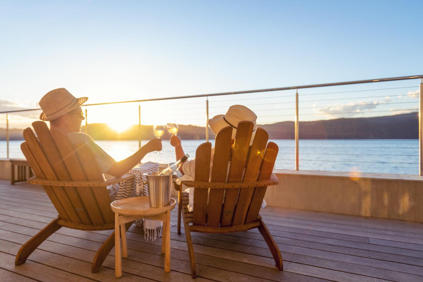 couple sitting on porch at beach drinking wine
