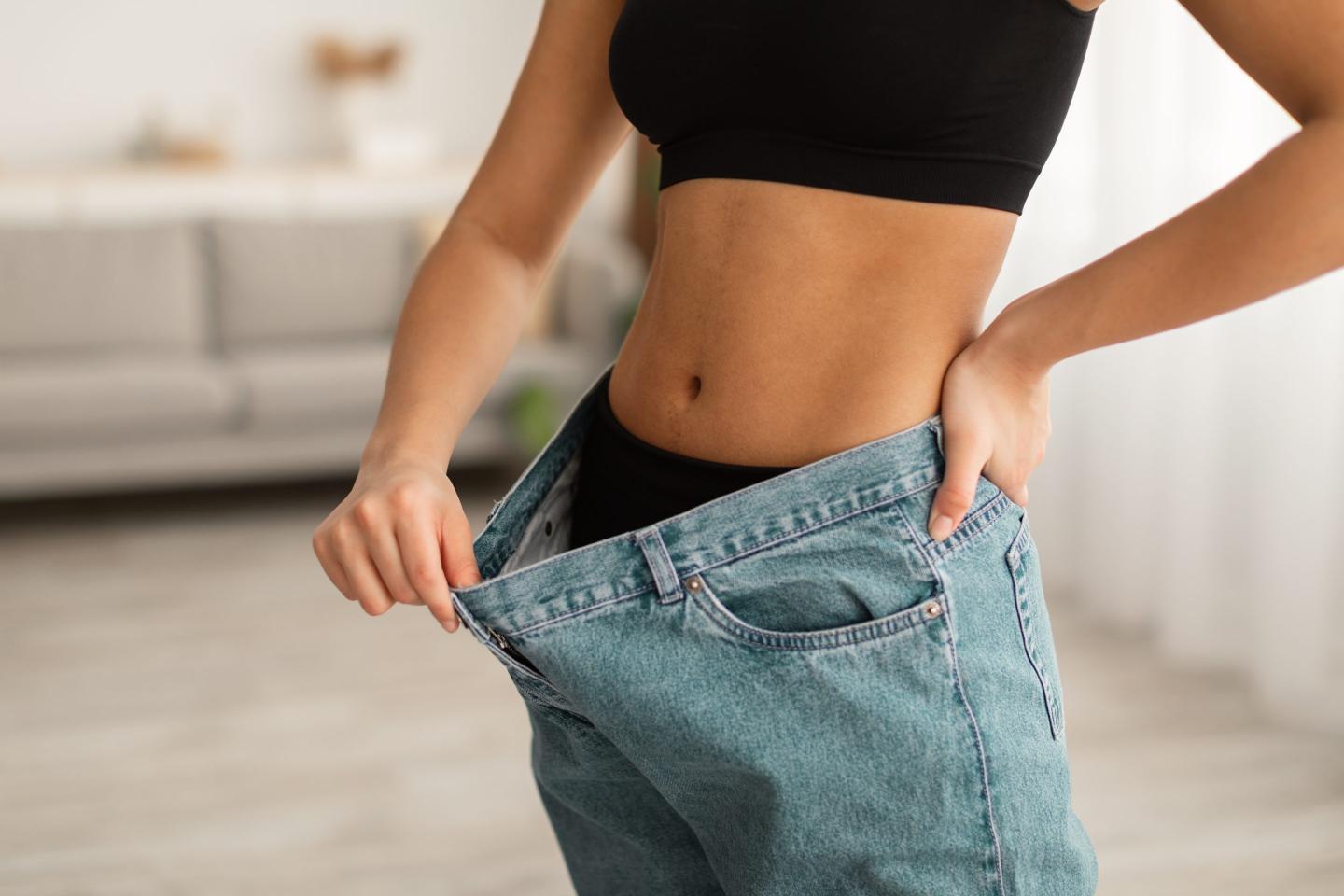 woman shows off old oversized jeans