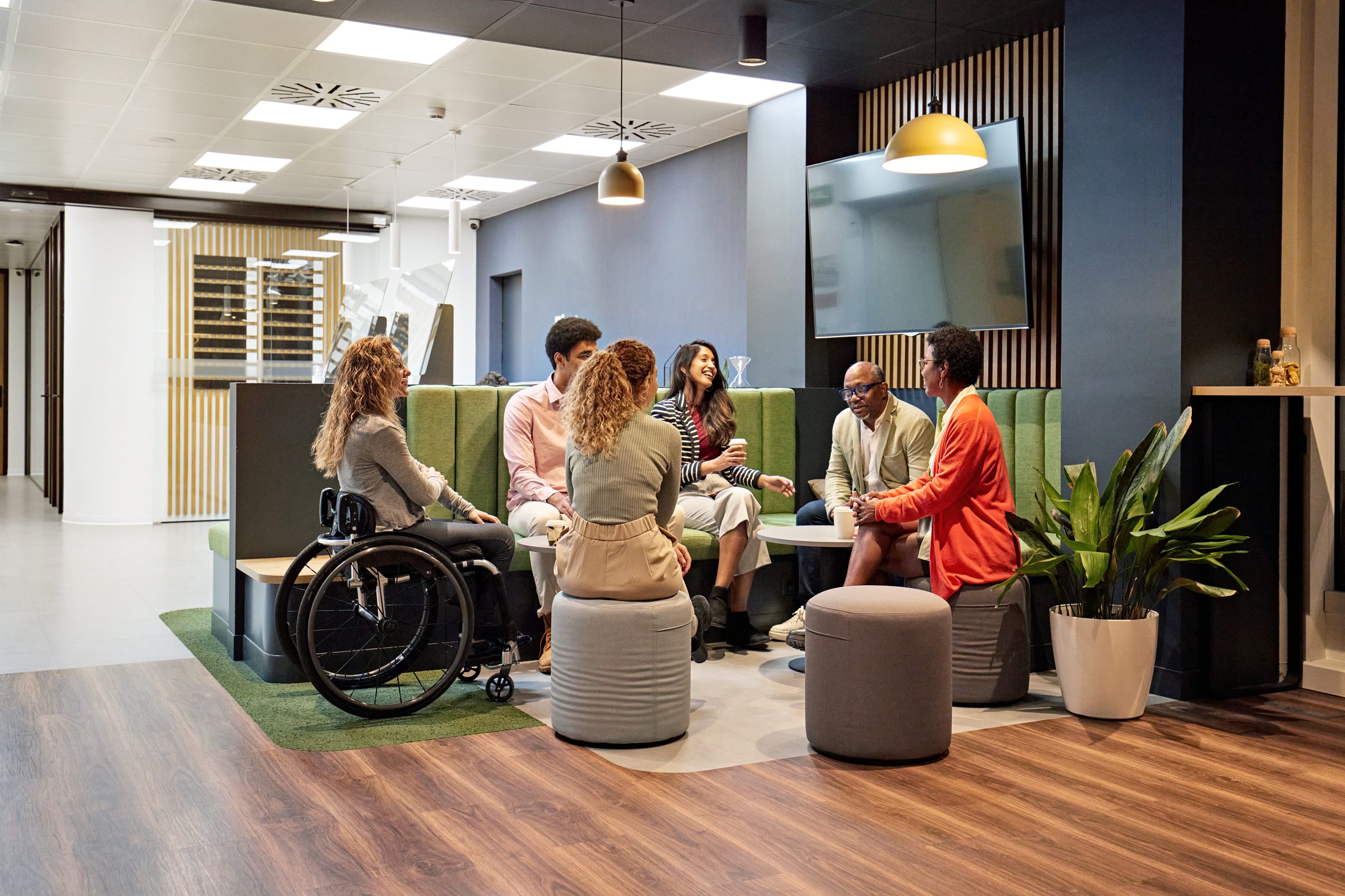 Six colleagues sit together at a lounge area in an office.