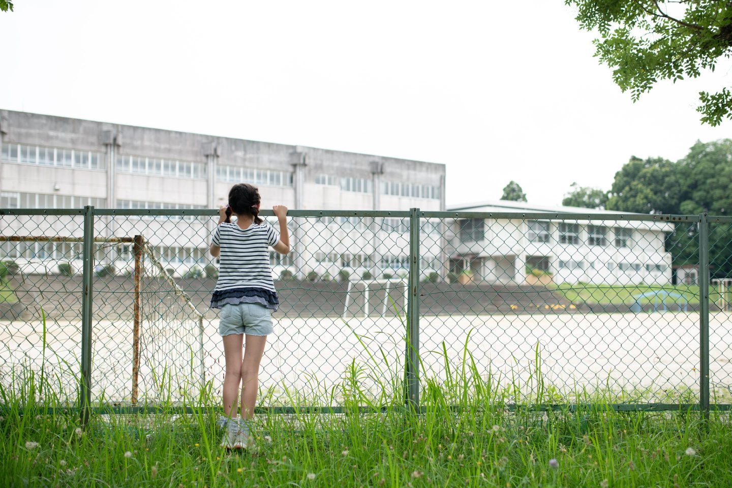 Child looks at empty schoolyard