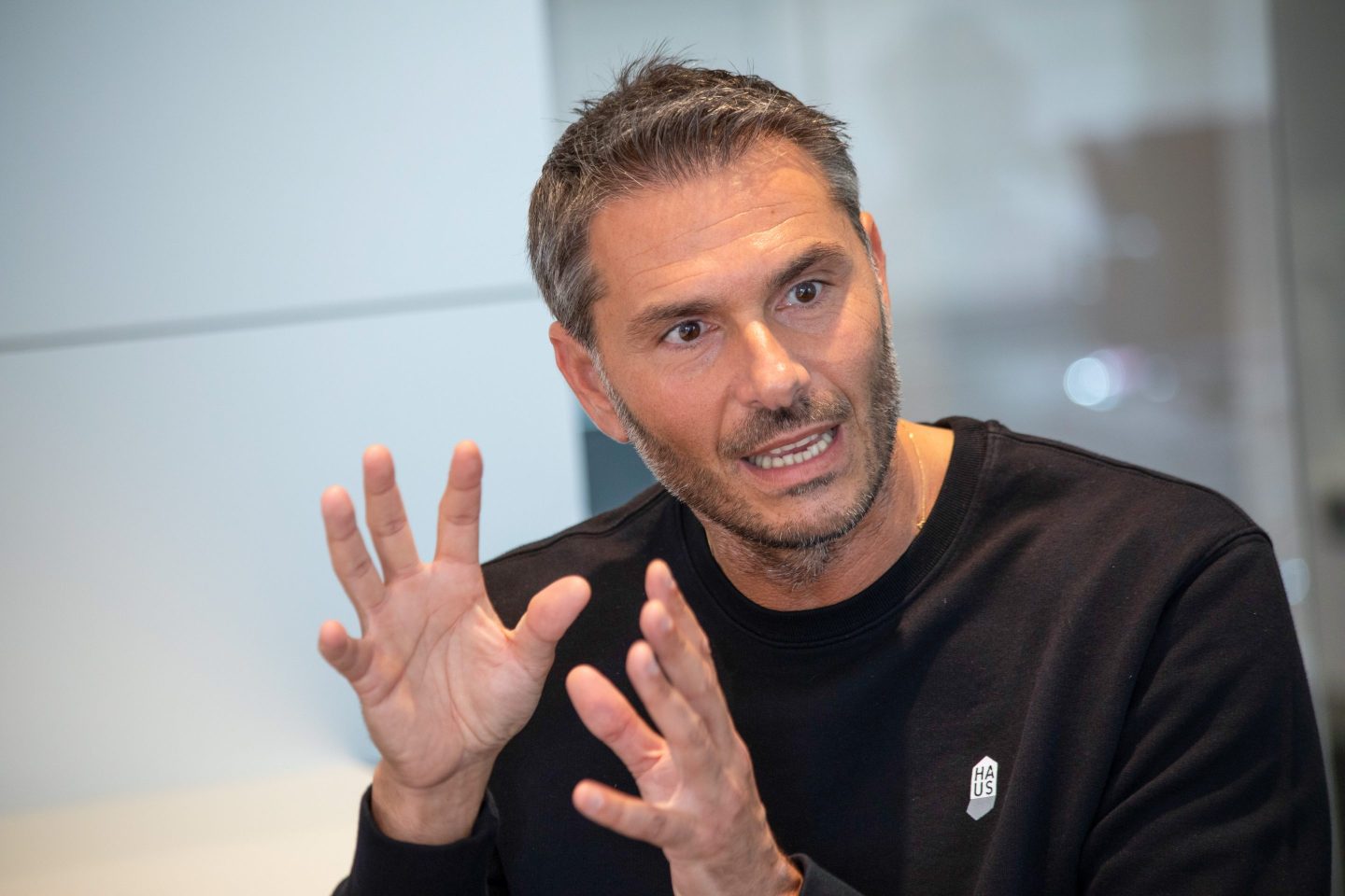 Golden Goose CEO Silvio Campara is wearing a black shirt and gesturing with both hands as he speaks.