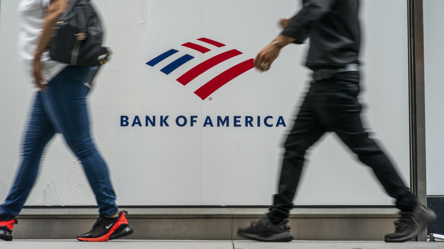 people walk past Bank of America sign