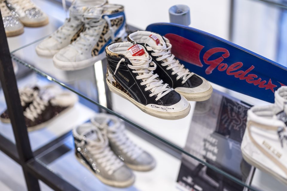 Black, white, and silver sneakers on display on a glass shelf.