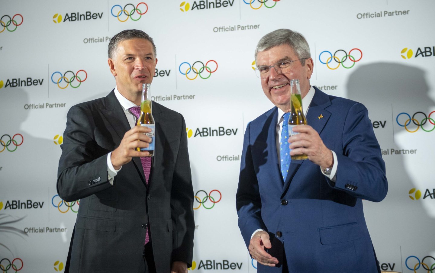 Anheuser-Busch InBev CEO Michel Doukeris, left, toasts with the head of the International Olympic Committee, Thomas Bach, their new partnership to promote non-alcoholic beers.