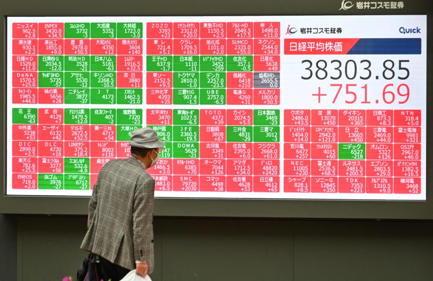 man looks at an electronic board displaying stock prices