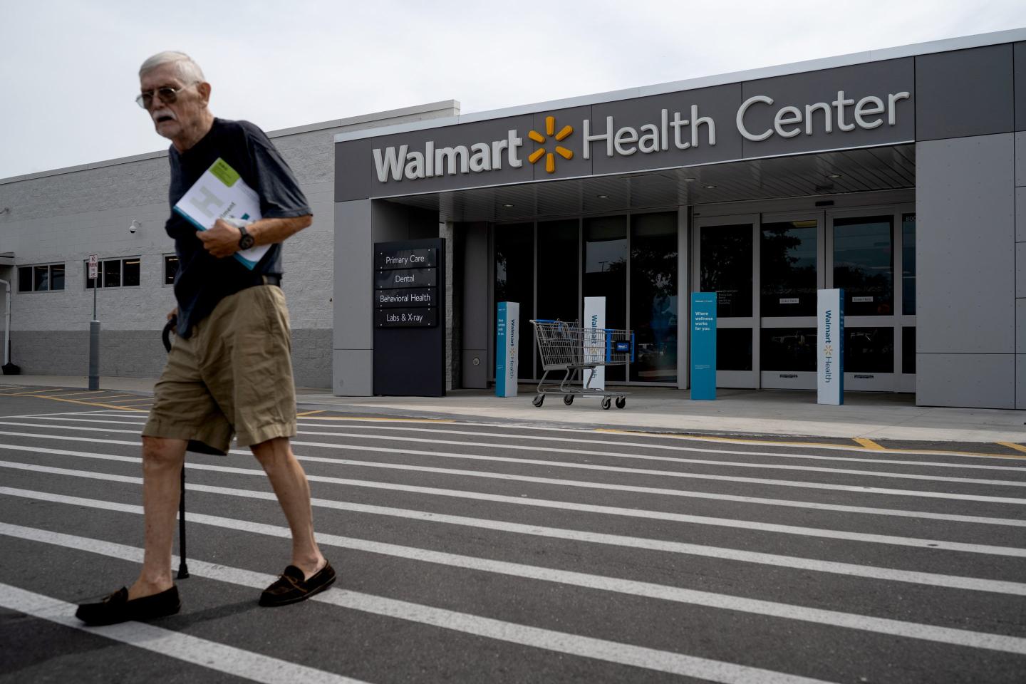 A senior citizen walks across a crosswalk outside a Walmart Health Center location in Florida.