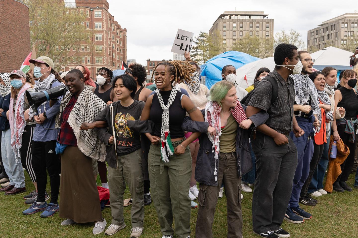 Student protesters lock arms at an campus encampment.