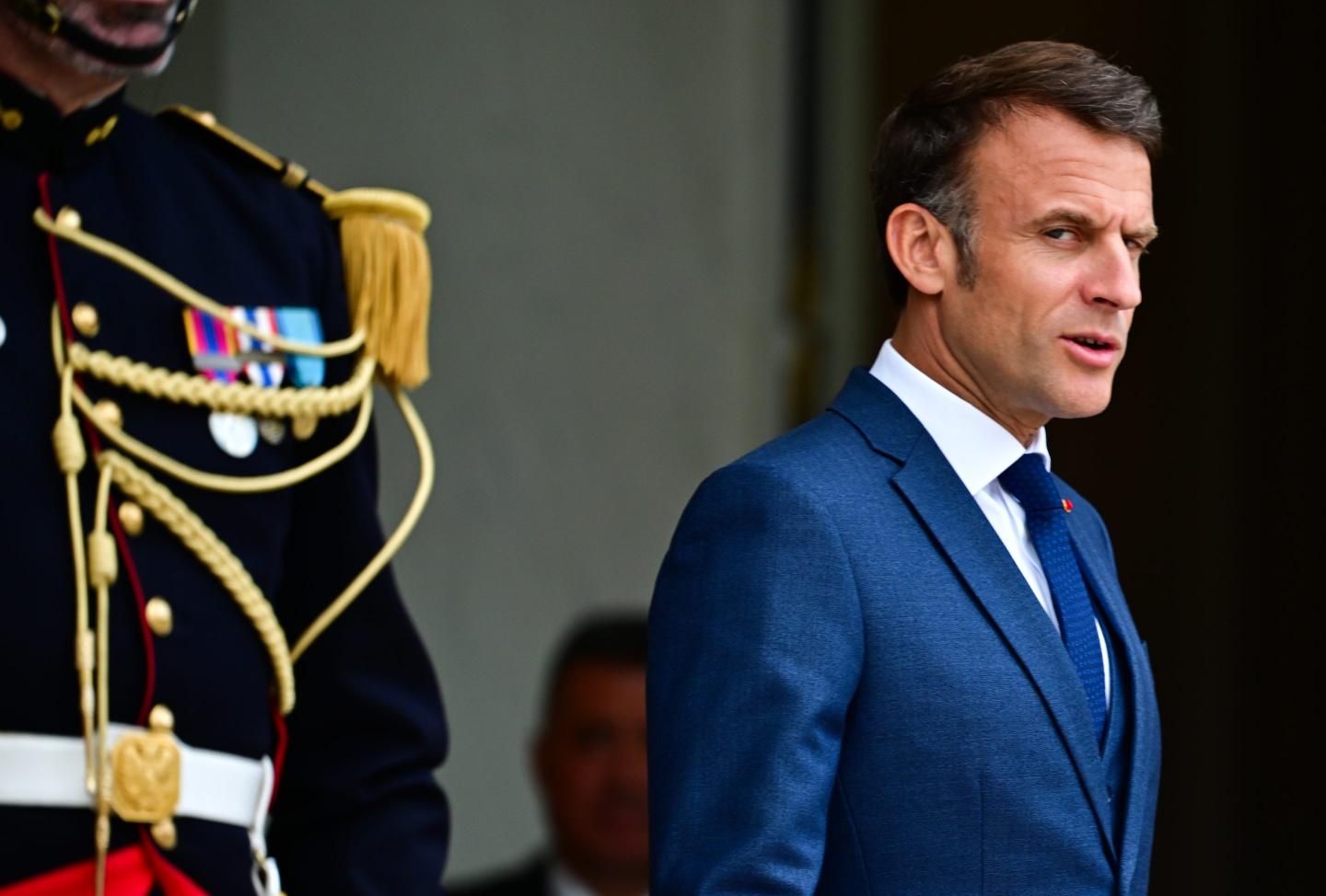 Emmanuel Macron stands next to ceremonial guard