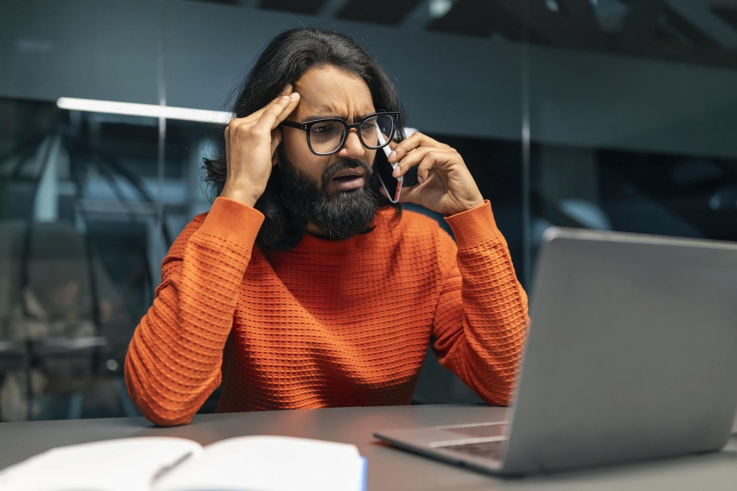Overwhelmed IT professional talking on phone