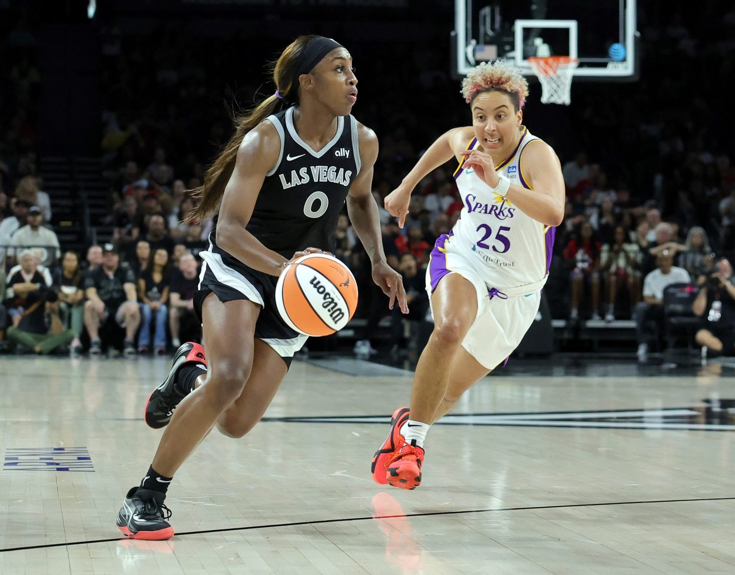 Las Vegas Aces player Jackie Young dribbles the ball up the court as Los Angeles Sparks player Layshia Clarendon chases her.