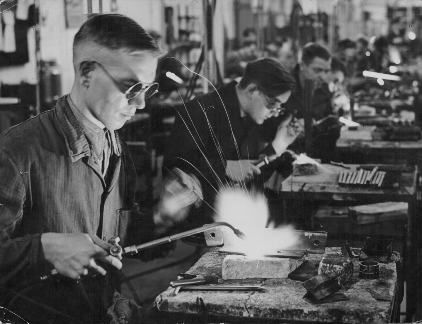 a row of men welding at a factory