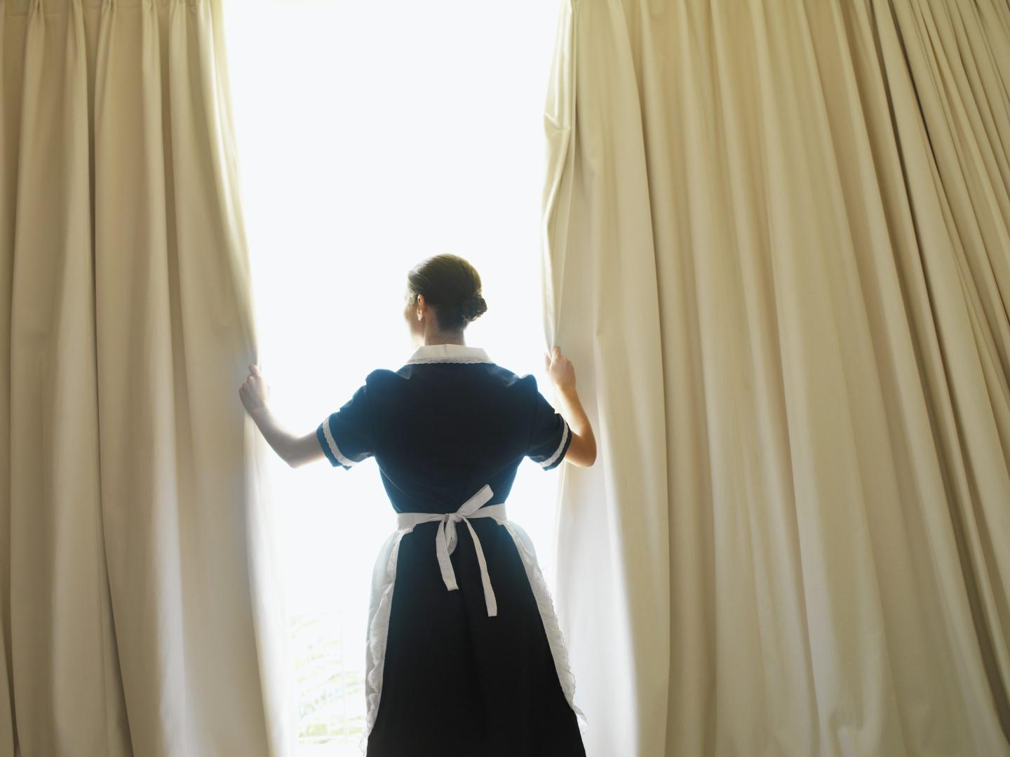 Hotel maid opening curtains