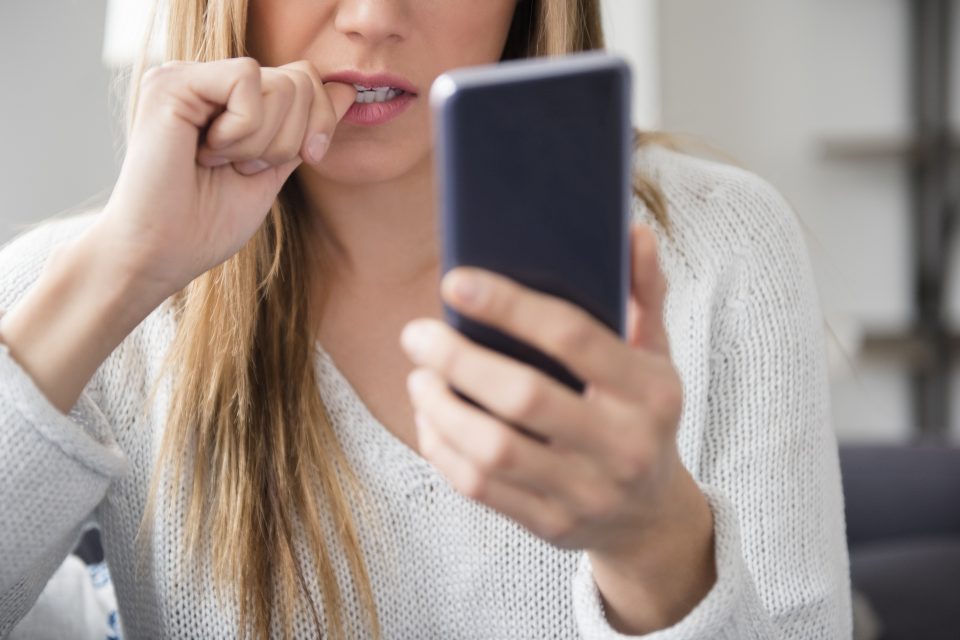 Nervous young woman using smartphone.