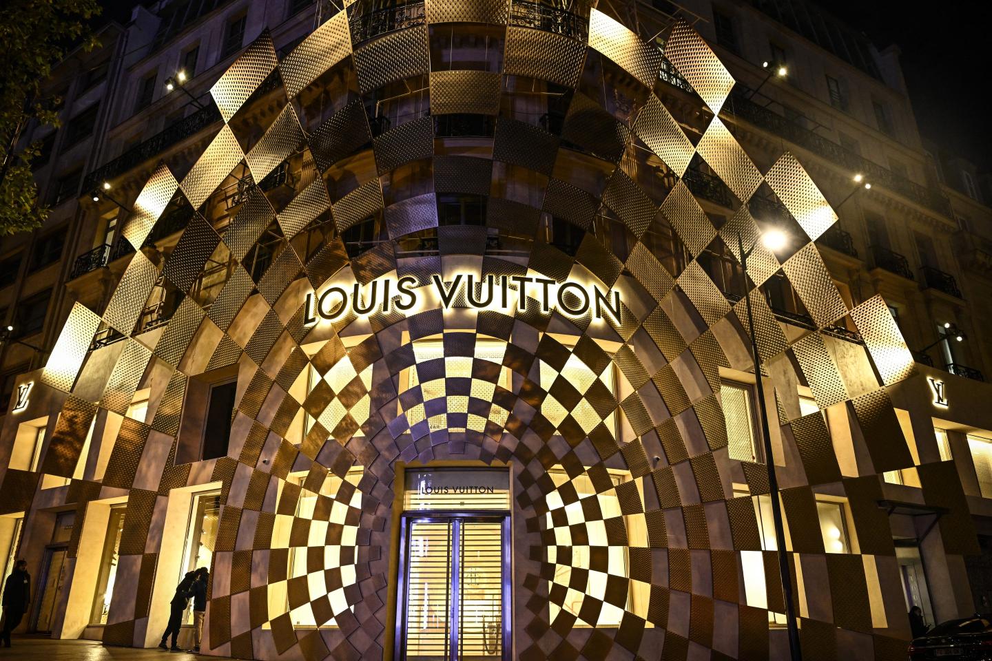 The front entrance of a Louis Vuitton store, illuminated at night.