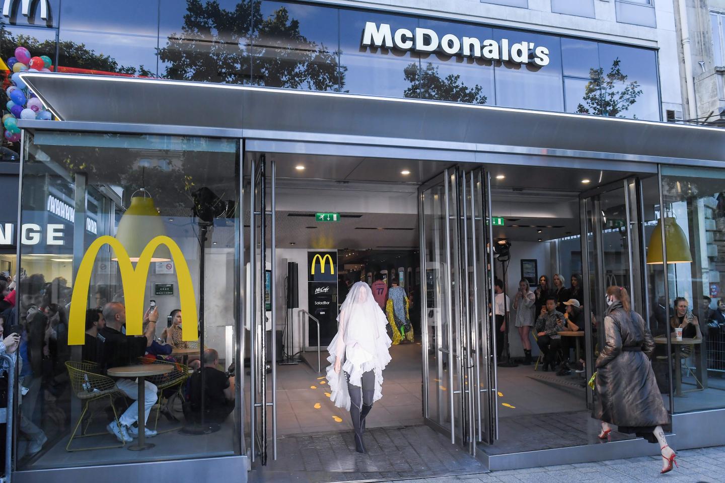 A model in long white veil exits a McDonald's.