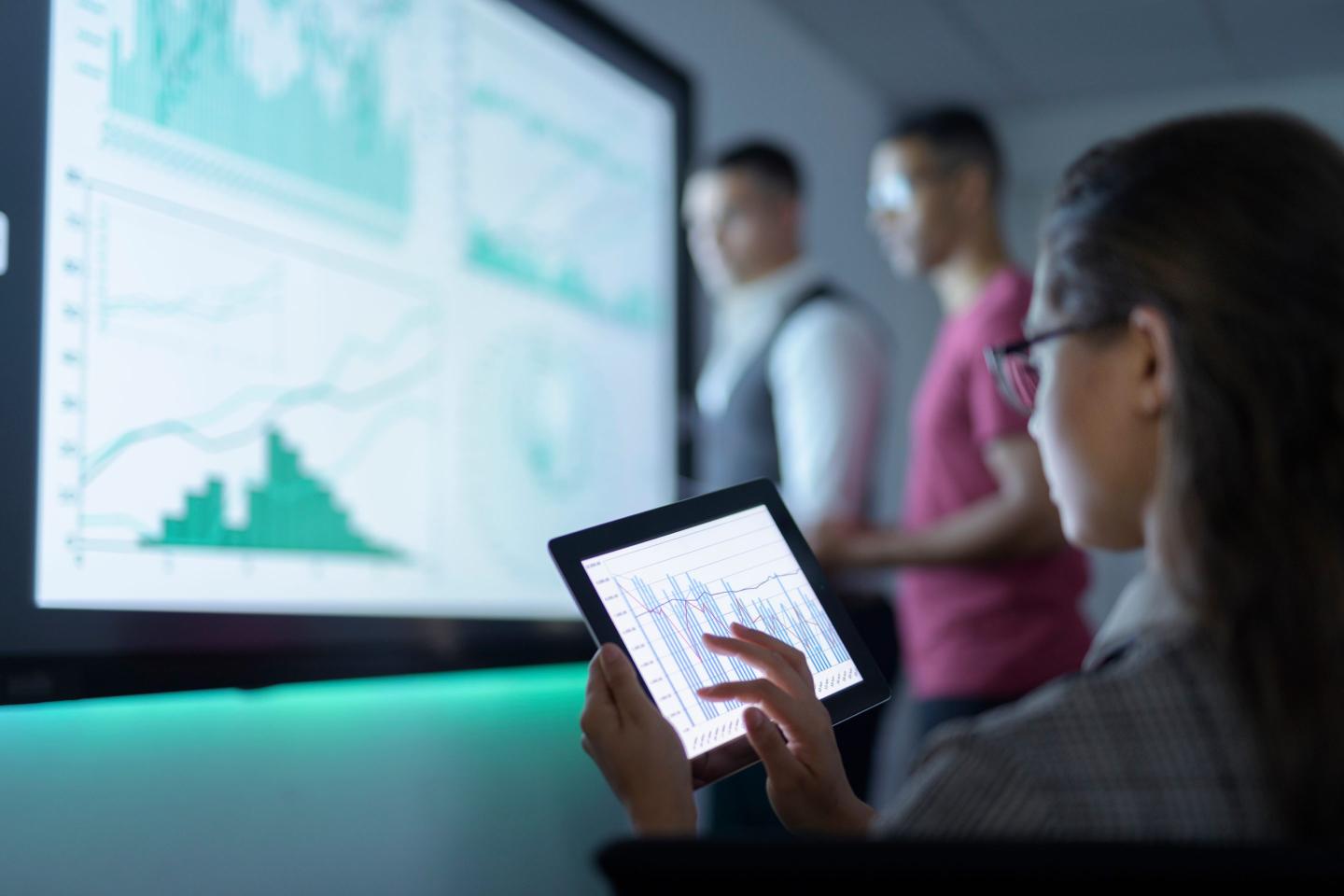Businesswoman viewing graphs on digital tablet in business meeting.